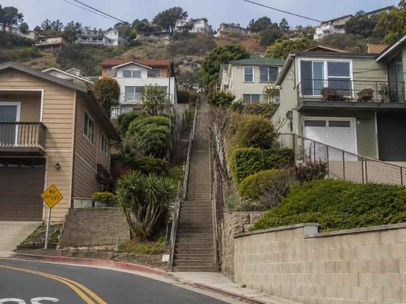 Public stairway running between hillside homes with curved streets and tiered retaining walls